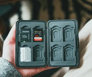 A memory card holder with various SD cards inside, held in a person's hand.